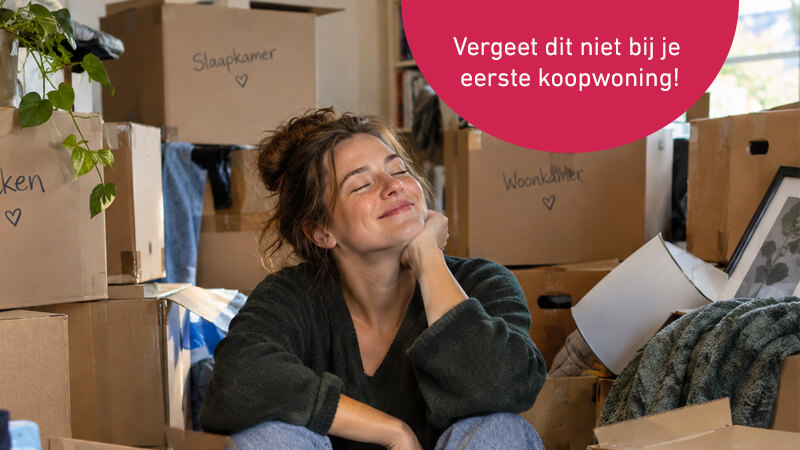 Tevreden jonge vrouw tussen de verhuisdozen na aankoop eerste koopwoning